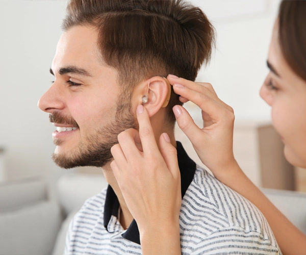 Junger Mann mit modernen Hörgerät bei der Akustikerin